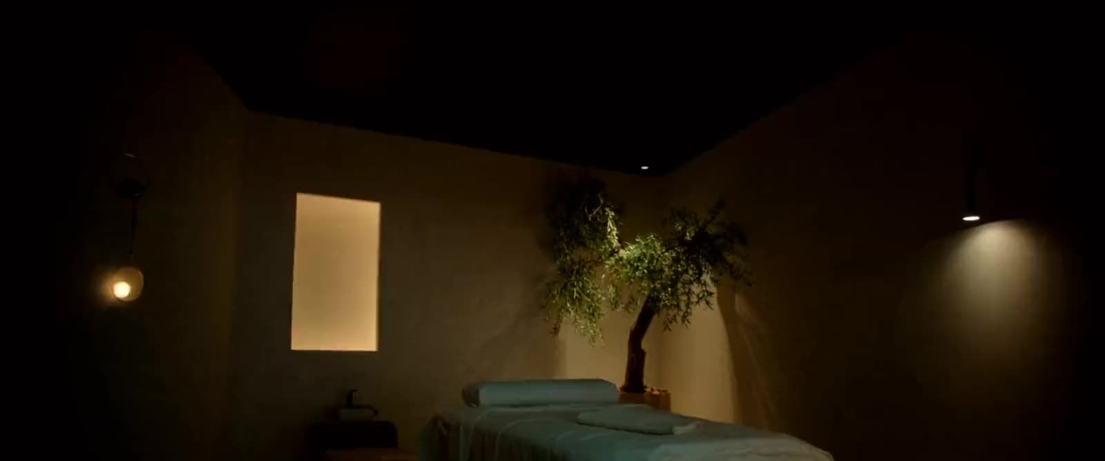 Luxury medspa treatment room with a sculptural treatment bed, soft plaster walls and warm sconce lighting